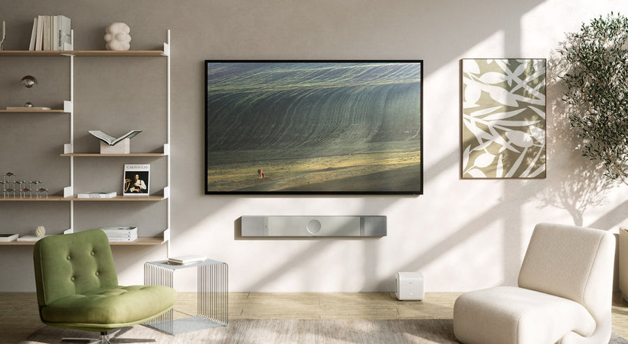 Salon moderne avec téléviseur mural et barre de son KEF élégante, illustrant une installation home cinéma haut de gamme éclairée par la lumière naturelle.