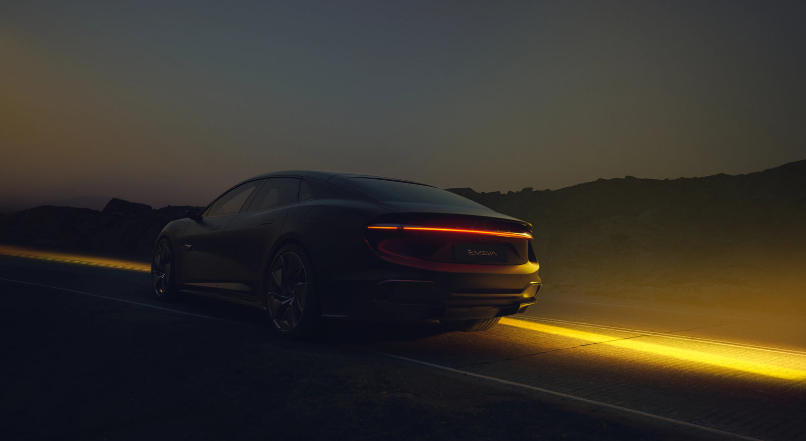 A dark luxury Lotus sports car shown from a rear three-quarter angle on a road at dusk, with glowing red taillights and a bright yellow light strip on the road below.
