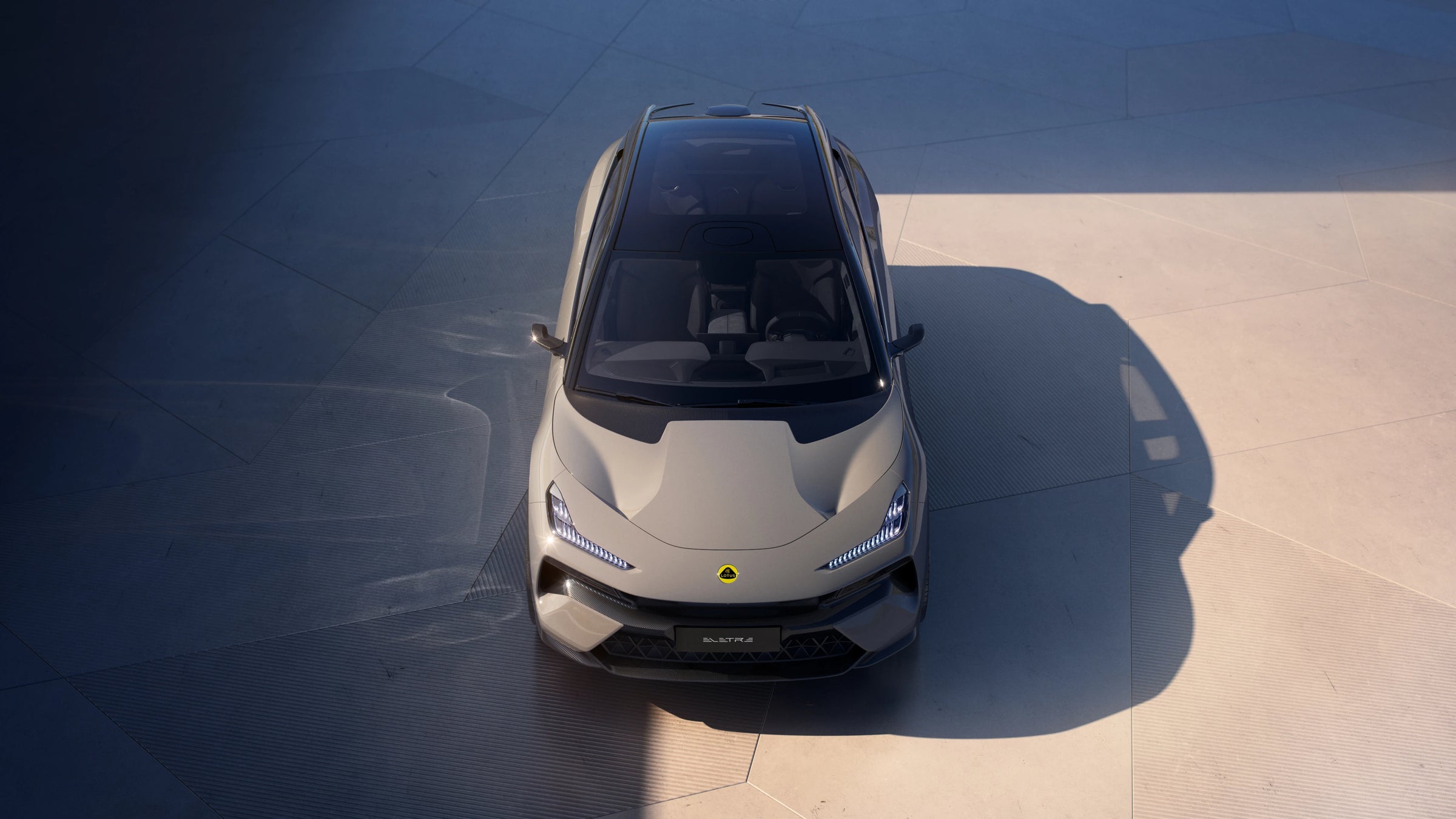 A top-down view of the Lotus Eletre parked on a concrete surface under direct sunlight.